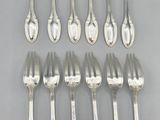 eight silverplated forks and spoons are arranged on a gray surface