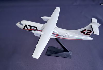 une maquette d'avion posée sur un socle, sur une surface bleue