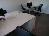 un bureau blanc sur lequel sont posés deux ordinateurs, dans un bureau