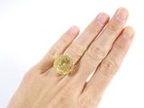 a woman ' s hand holding a gold ring with a coin on it