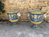 two blue and yellow vases sitting next to a brick wall