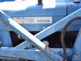 a close up of a blue tractor that is parked in the dirt