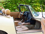a white car with a tan interior parked in front of a bush