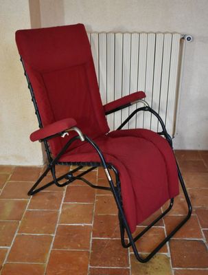 une chaise longue rouge dans une pièce avec un radiateur