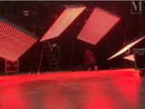 Deux personnes se tiennent sur une scène éclairée par des lumières rouges.