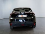 the rear end of a black car in a room with a white wall