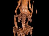 wooden sculpture of a woman with a hat and a fish on a rock
