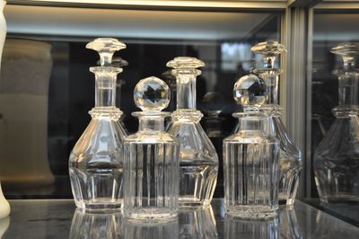 five clear glass bottles sitting on a glass shelf