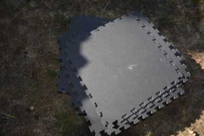un tapis noir posé par terre, à côté de l'ombre d'une personne
