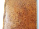 an old brown leather book sitting on top of a white table