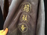 a person that is holding a jacket with chinese writing on it