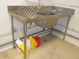 a stainless steel sink in a kitchen next to a trash can