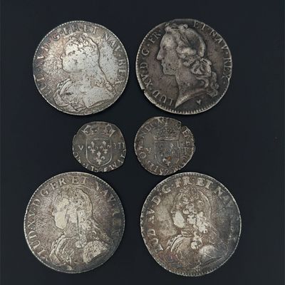 six pièces d'argent de tailles et de formes différentes sur un fond noir