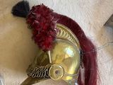 un casque doré surmonté d'une plume rouge