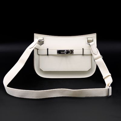 a white leather bag with a metal clasp on a black background