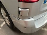 the rear end of a silver car with a blue license plate on it