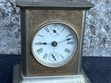 a small silver clock with roman numerals on it