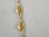 a close up of a gold necklace on a white surface