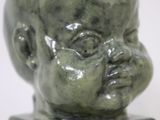 a small green statue of a baby on a block