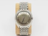 a close up of a watch on a wooden stand on a white surface