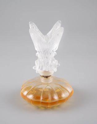 un flacon de parfum en verre orange surmonté d'un papillon
