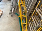 yellow and green ladders are stacked next to each other in a garage