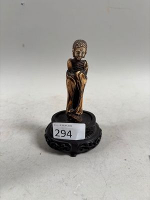 une image représentant une petite statue d'une personne assise sur un socle