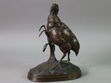 bronze statue of a bird on a rock on a white background