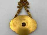 a close up of a gold clock hanging on a white wall
