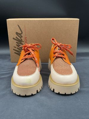 une paire de baskets orange et blanches avec une boîte en arrière-plan