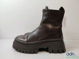 des bottines en cuir marron à semelles en caoutchouc, posées sur un fond blanc