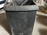 a black trash can sitting in a garage next to a white truck