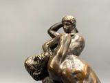 bronze statue of a man wrestling a woman on a marble base
