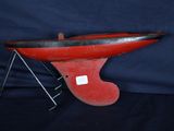un vieux bateau rouge et noir posé sur un socle métallique