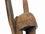 wooden sculpture of a man ' s head wearing a helmet with a long nose