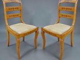 deux chaises en bois avec des assises rembourrées beiges sur fond gris