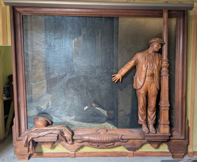 une statue représentant un homme debout devant un tableau