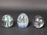 three glass marbles sitting on top of a table next to each other
