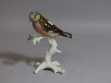 a small figurine of a bird sitting on a branch