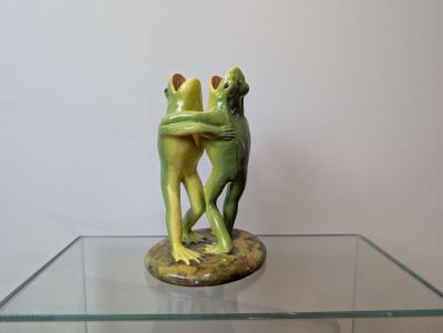 une statue représentant deux grenouilles enlacées, posée sur une table en verre