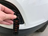 a person holding a measuring tape to measure a car ' s tire