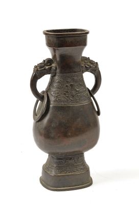 un vase en bronze posé sur une surface blanche