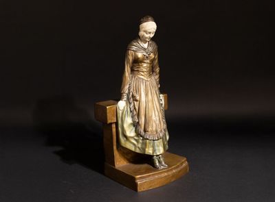 une petite statue représentant une femme assise sur un banc