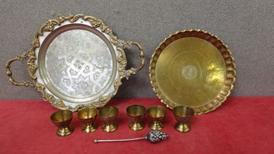 deux plateaux en argent et des tasses à anse posés sur une nappe rouge
