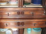 a wooden cabinet with many plates and bowls on top of it