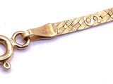 a close up of a gold bracelet on a white surface