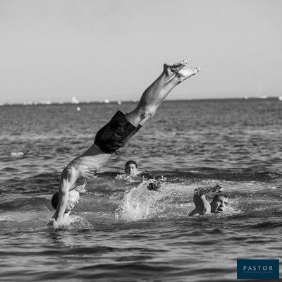 photographie en noir et blanc d'un homme faisant le poirier dans l'eau