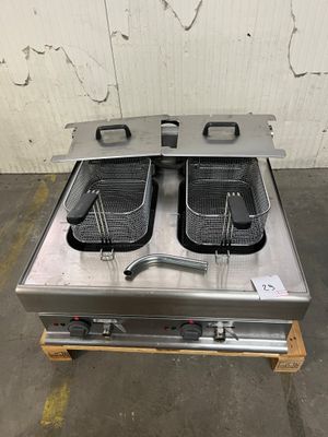 deux friteuses posées sur une palette dans un entrepôt