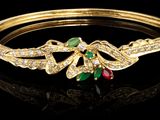 un gros plan sur un bracelet en or orné d'émeraudes et de rubis