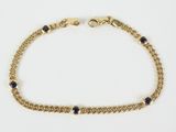 a close up of a gold chain bracelet with blue stones